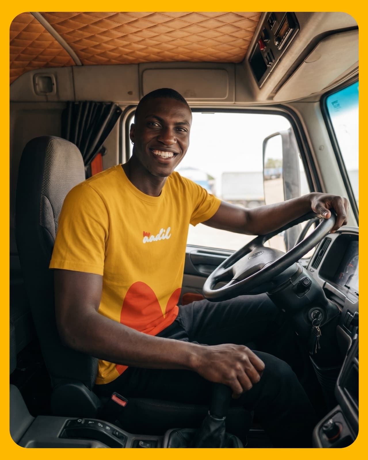 Driver in an Aadil branded tee at the wheel of the truck