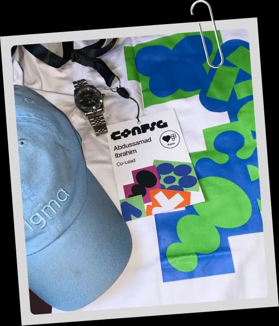 Flatlay of a Config lanyard badge, cap, watch and printed tee