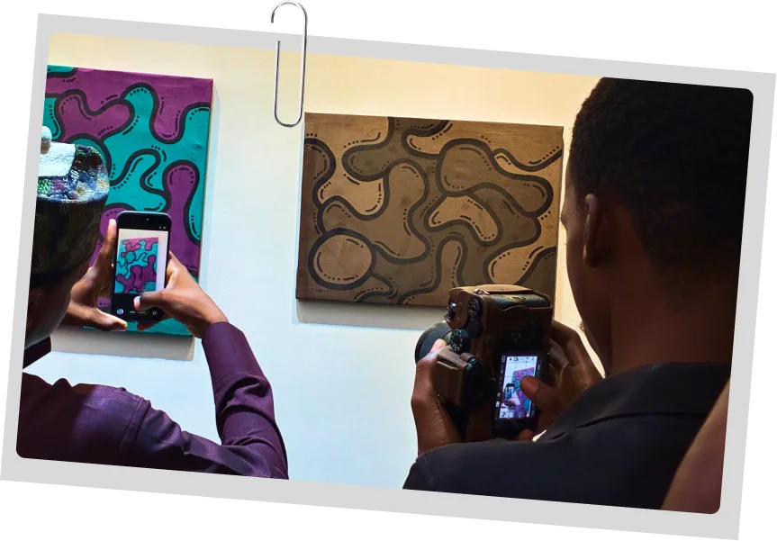 Two visitors photographing painted canvases hung on a gallery wall