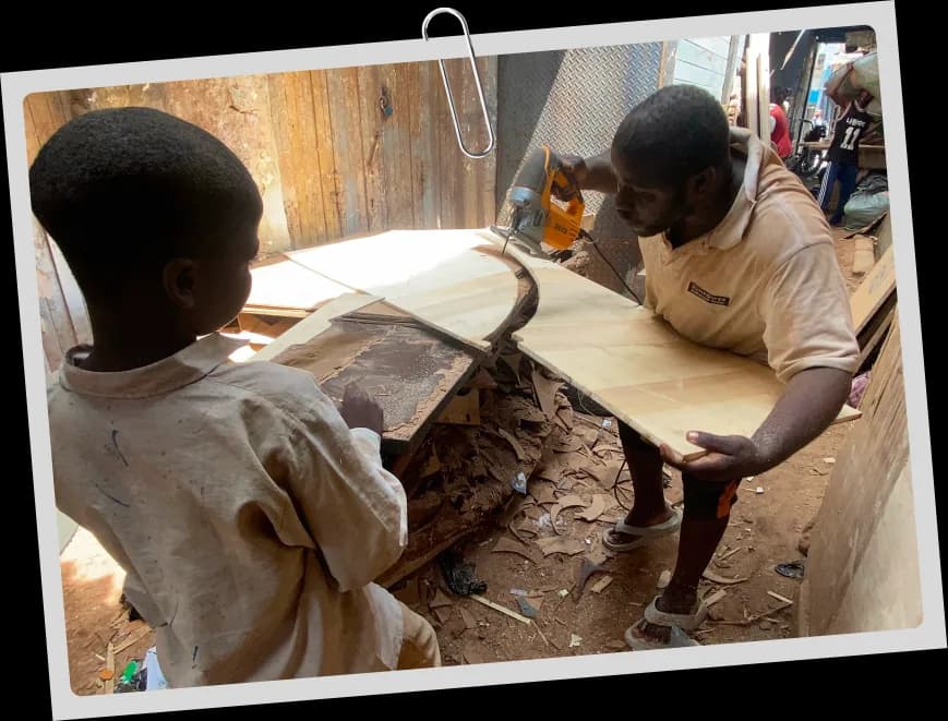 Cutting plywood for a skate ramp while a young helper steadies the sheet